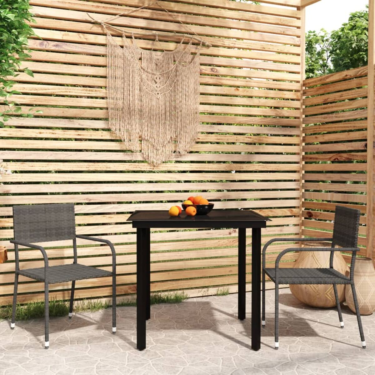 Essgruppe im Freien mit schwarzem Tisch und zwei grauen Stühlen. Orangen auf dem Tisch, Holz-Hintergrund.