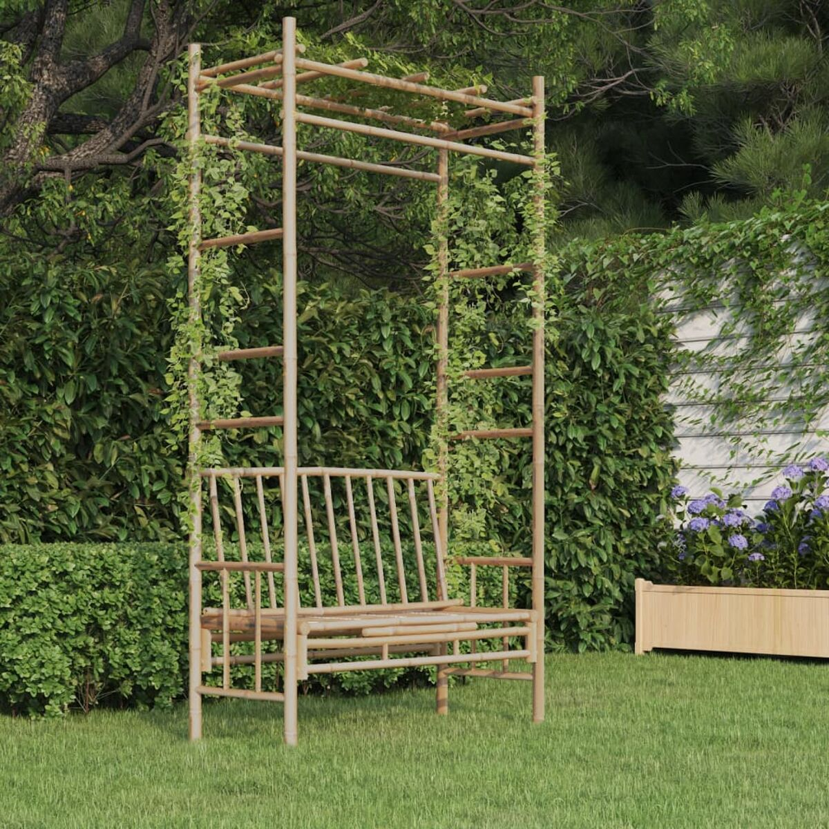 Eine Bambusbank mit Spalier, bedeckt mit grünen Ranken, auf Gras. Der Himmel ist sichtbar.