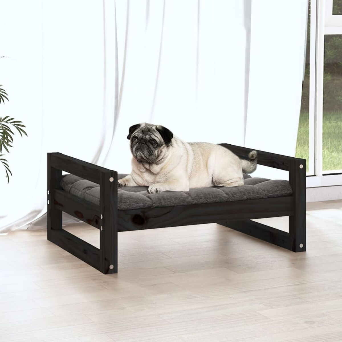 Mops auf einem dunklen Haustierbett aus Holz, in der Nähe eines Fensters.