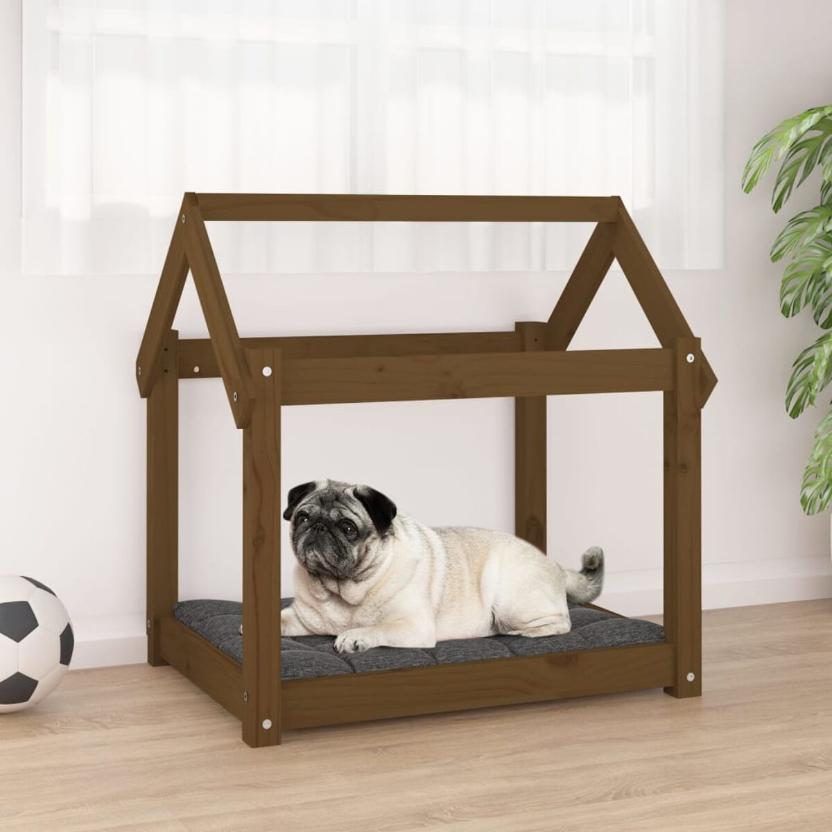 Hundehütte aus Holz mit Mops auf grauem Kissen. Ein Fußball in der Ecke.