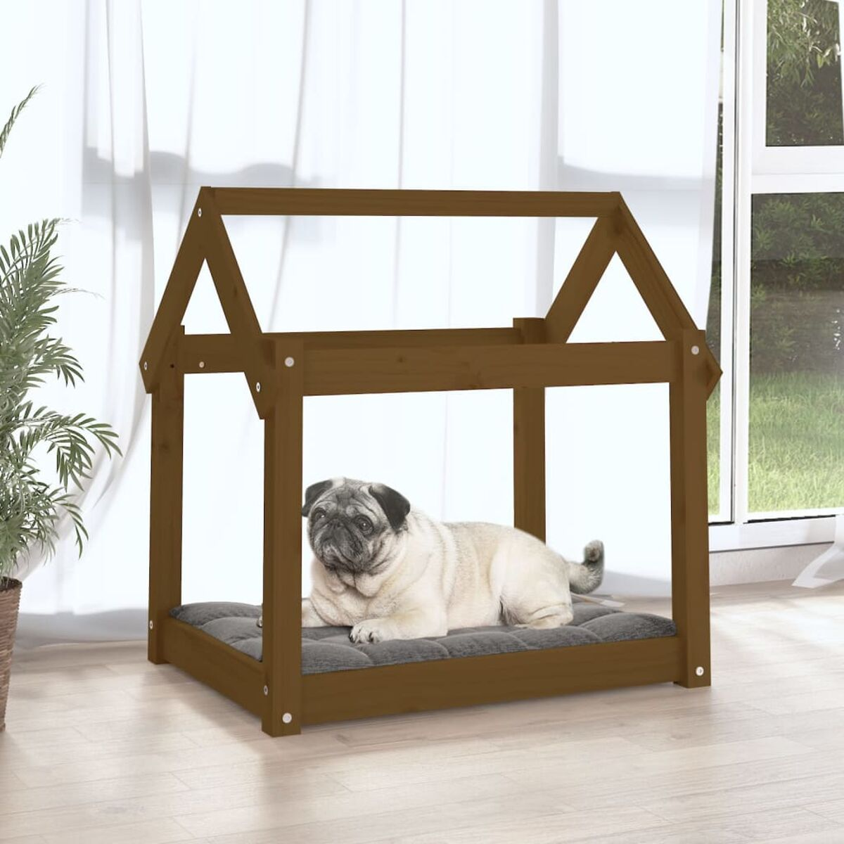 Ein braunes Hundehäuschen mit einem Mops, der auf einem grauen Kissen liegt. Im Hintergrund sind eine Pflanze und ein Fenster.