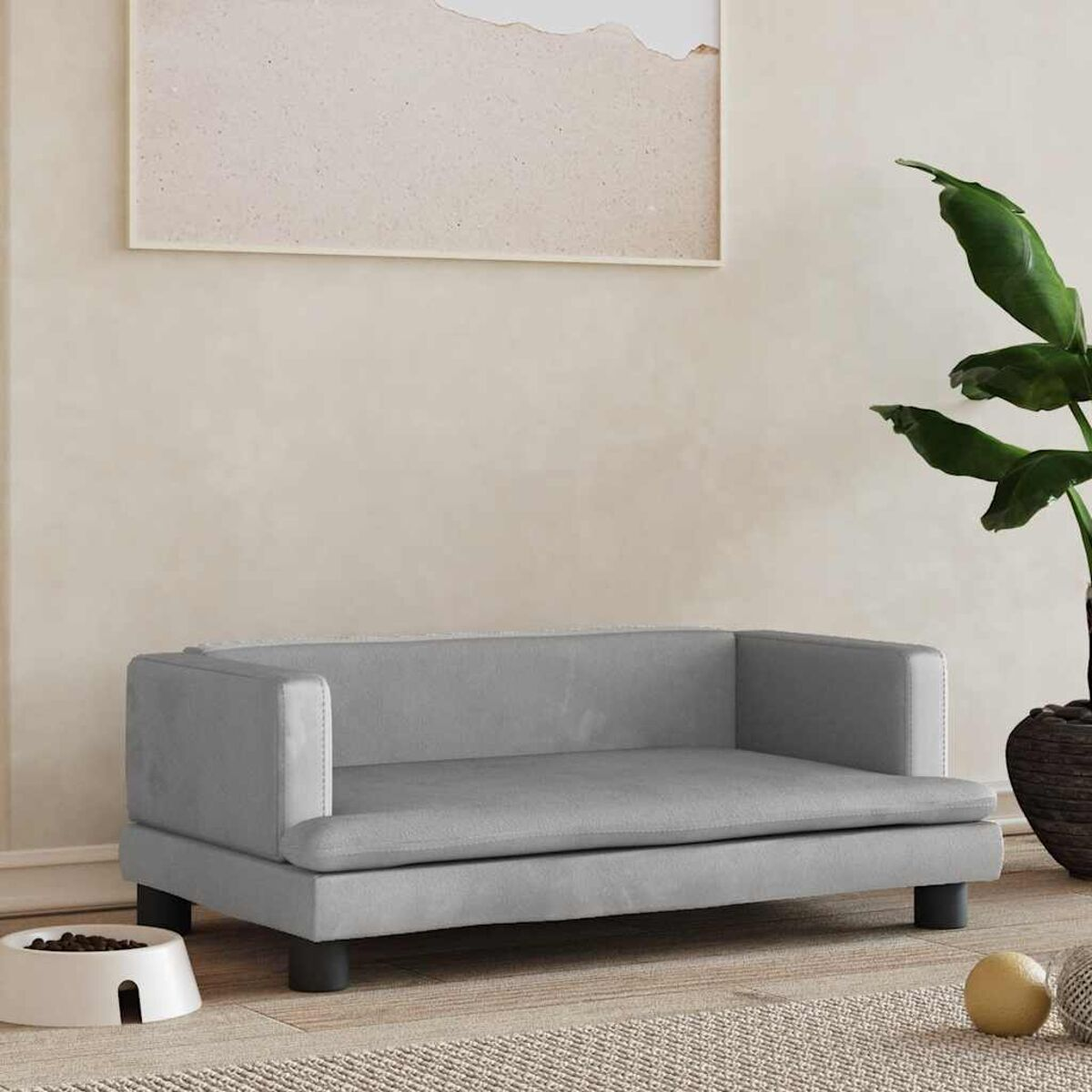 Ein graues Haustiersofa mit schwarzen Beinen, mit einer Futterschüssel und einer Pflanze in der Nähe.