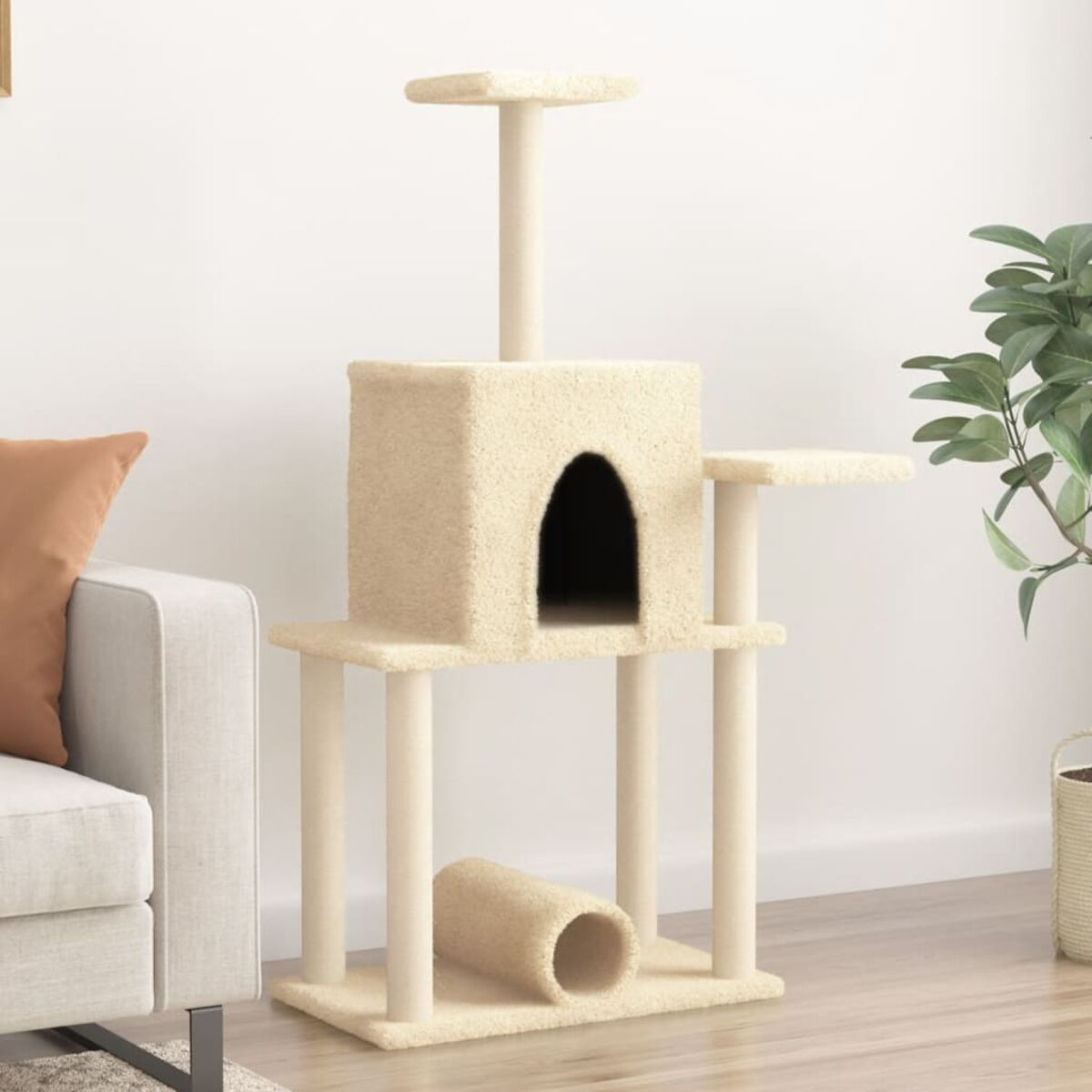 Beiger Katzenbaum mit mehreren Plattformen, einem Versteck und einem Tunnel. Neben einer Couch und einer Pflanze.