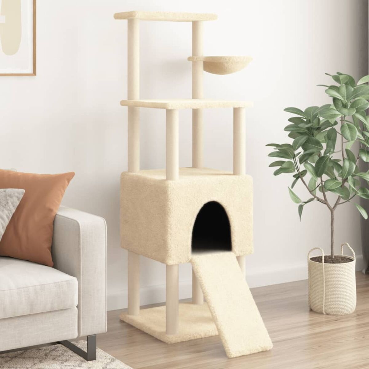 Beiger Katzenbaum mit mehreren Plattformen, einer Höhle und einer Rampe. Im Hintergrund ein Sofa und eine Pflanze.