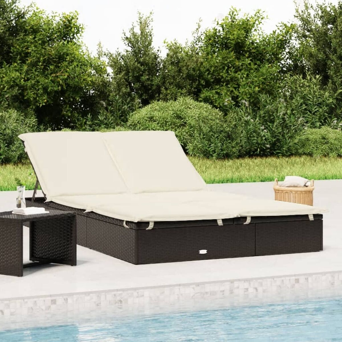 Doppelte Chaiselongue mit cremefarbenen Kissen neben einem kleinen Tisch in der Nähe eines Pools.