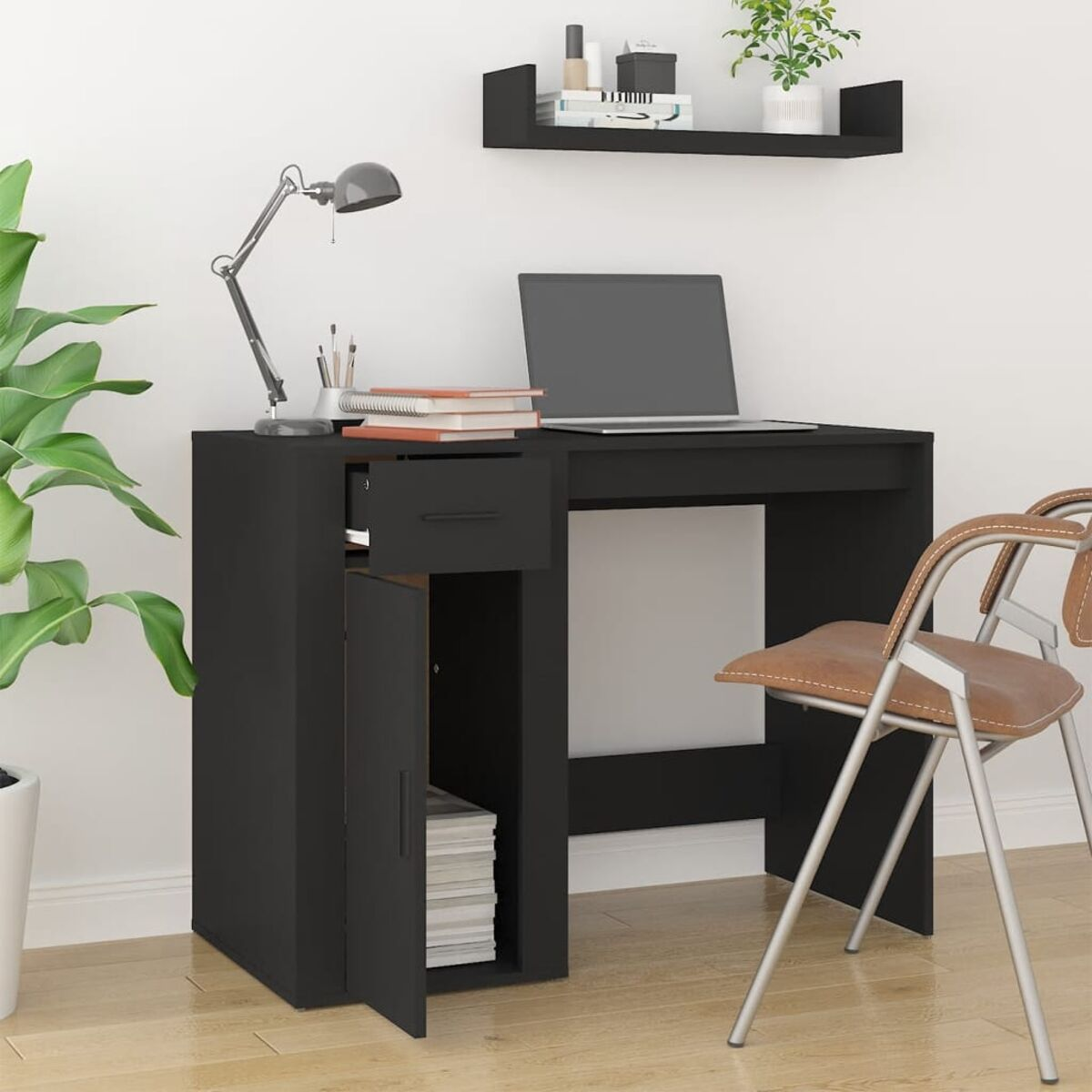 Ein schwarzer Schreibtisch mit offener Schublade, Tür und Laptop. Ein Stuhl befindet sich rechts, eine Pflanze links.