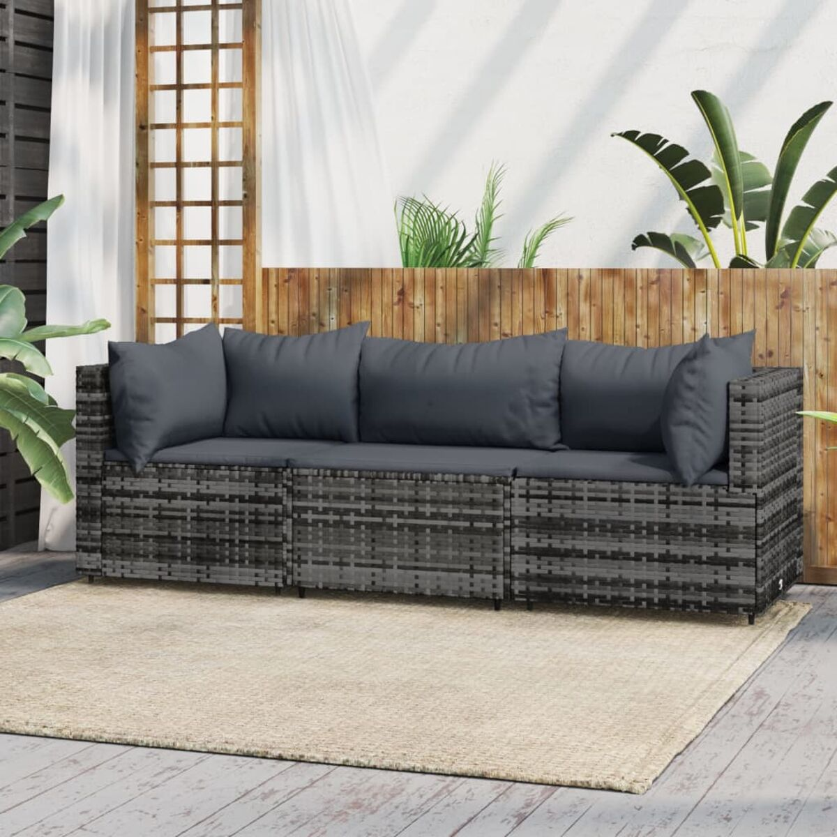 Graues Rattan-Sofaset mit dunkelgrauen Kissen. Das Sofa steht auf einem beigen Teppich.