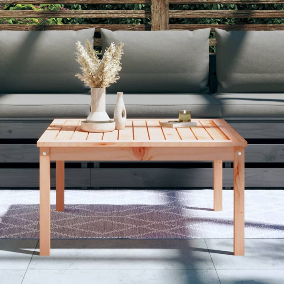 Holz-Couchtisch mit Pflanzen, auf einem Teppich, mit Sofa im Hintergrund.