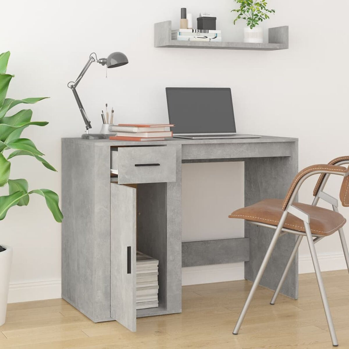 Ein grauer Schreibtisch mit Laptop und geöffneter Schublade. Ein Stuhl und eine Pflanze sind im Vorder- und Hintergrund.