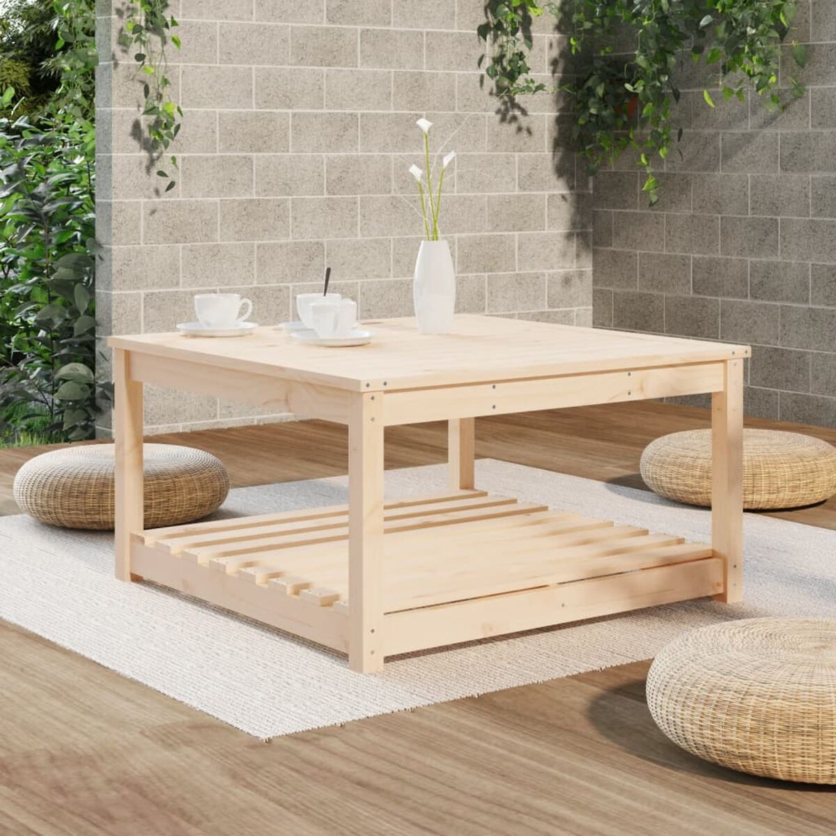 Quadratischer Couchtisch aus hellem Holz mit unterem Regal. Zwei Tassen, weiße Blumen.
