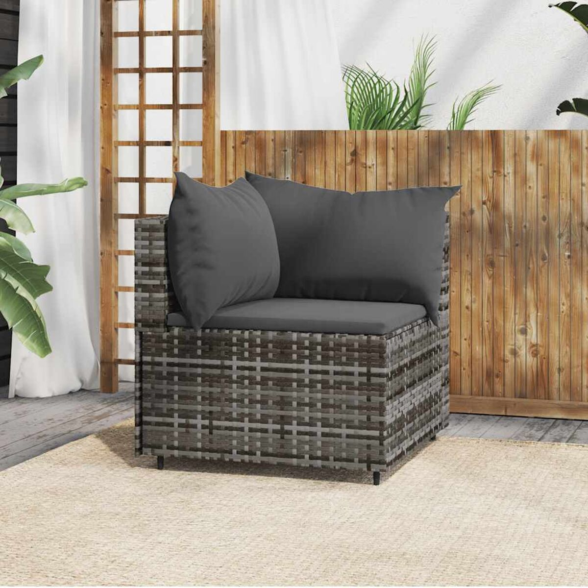 Ecksofa aus Korbgeflecht mit grauen Kissen, auf einem Teppich. Holz-Hintergrund.