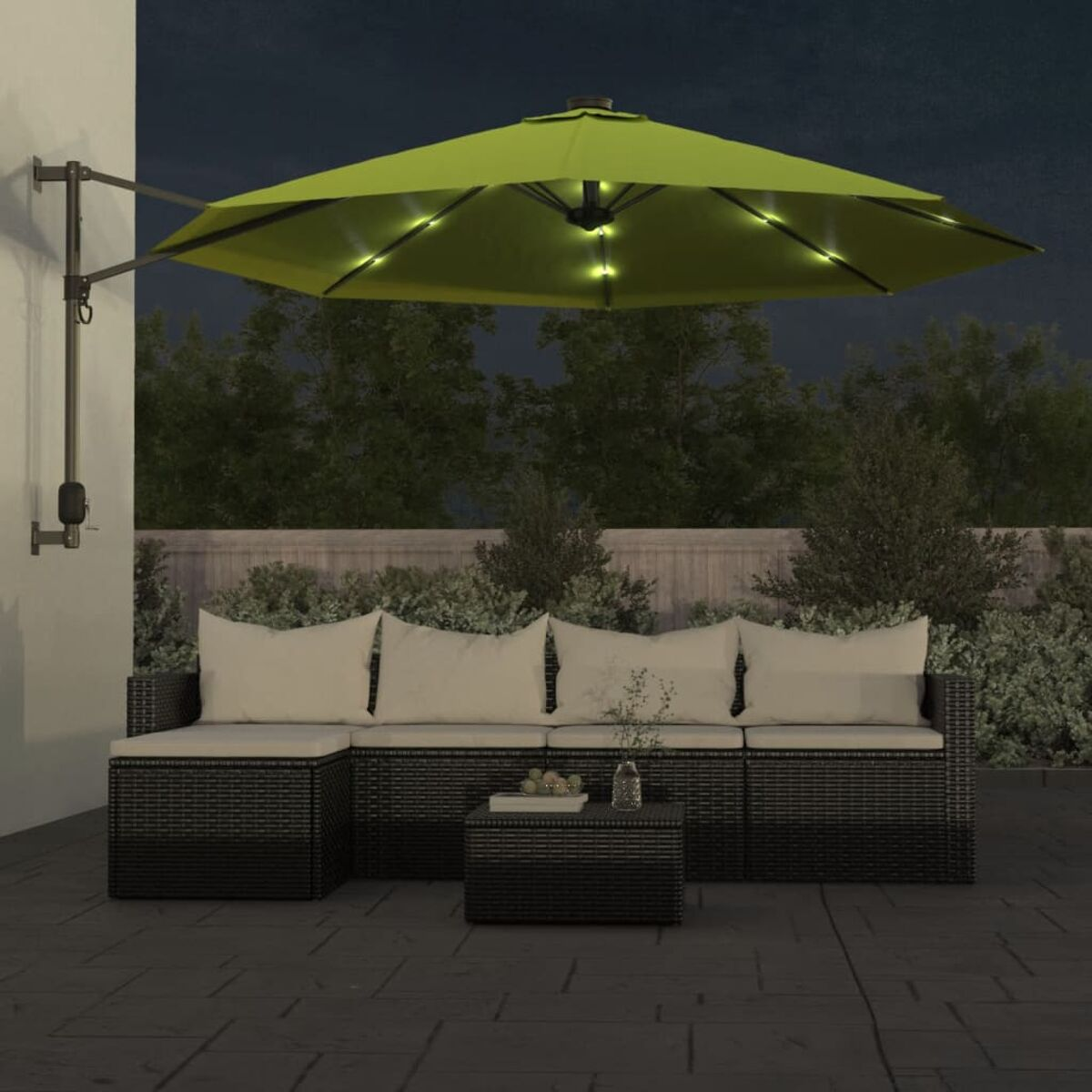 Ein schwarzes Outdoor-Ecksofa mit einem olivgrünen Regenschirm bei Nacht.