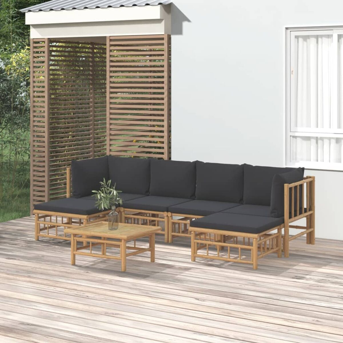 Ein Outdoor-Ecksofa aus Bambus mit dunklen Kissen und einem passenden Couchtisch.