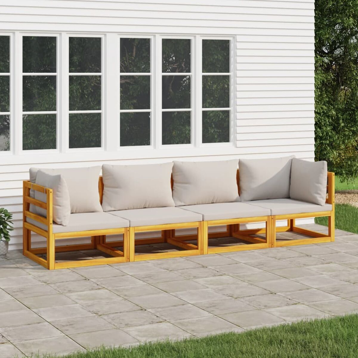 Holzsofa mit cremefarbenen Kissen auf einer Terrasse vor einem weißen Haus.