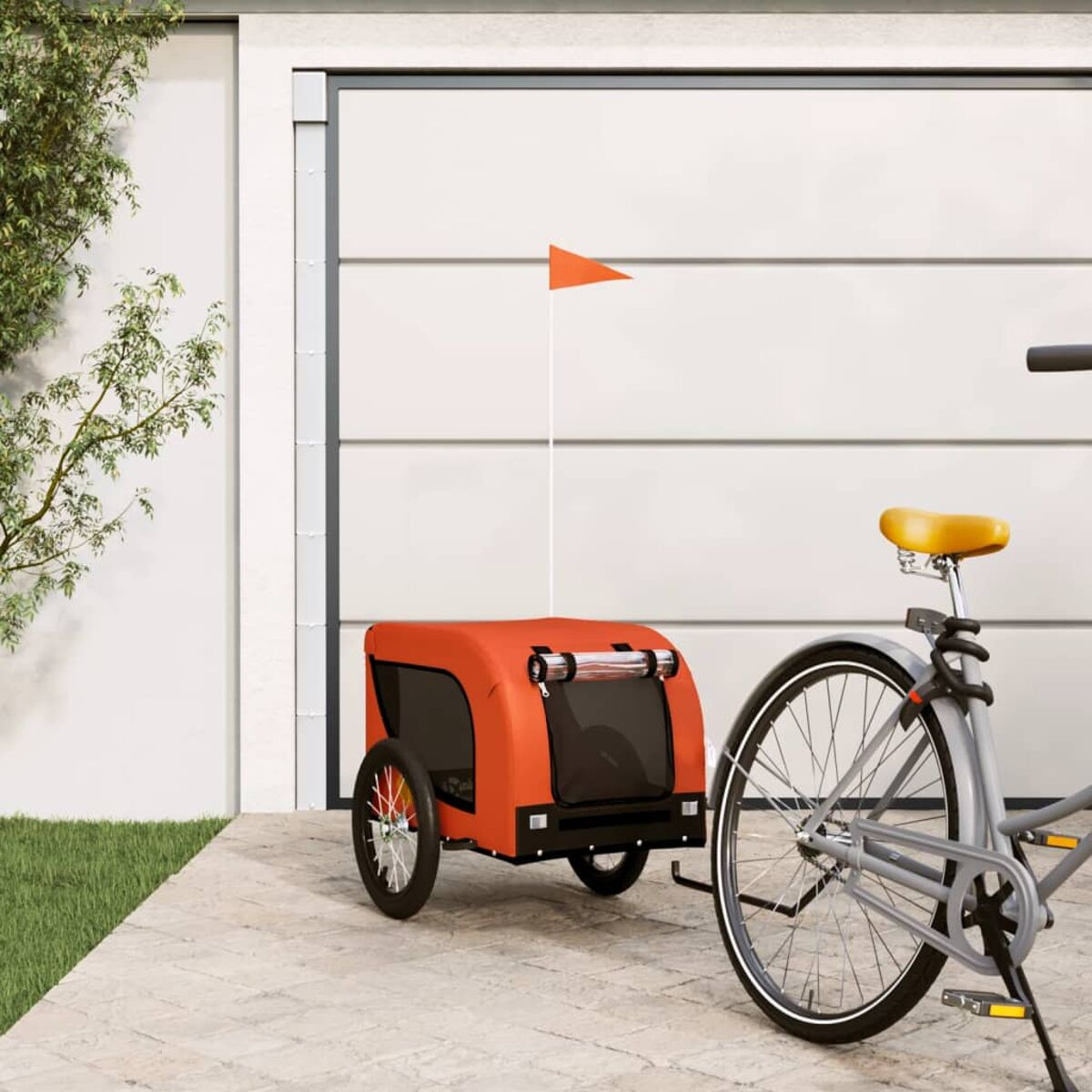 Ein Fahrrad zieht einen orangefarbenen Anhänger mit einer Flagge. Garagentor im Hintergrund.