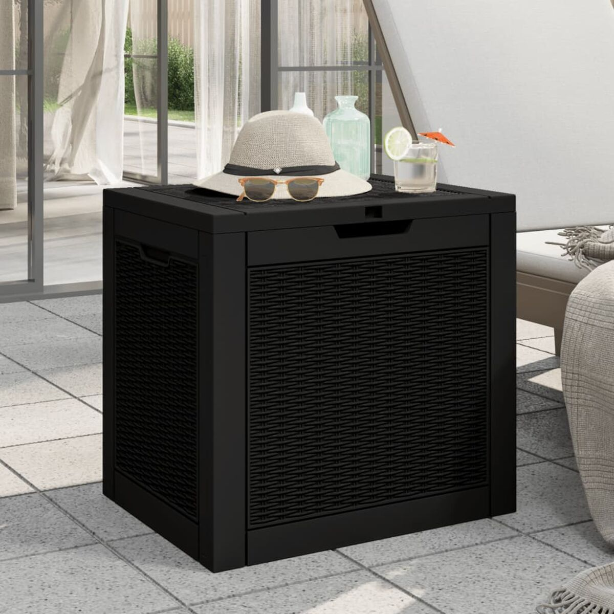 Eine schwarze Outdoor-Aufbewahrungsbox mit Webmuster auf der Frontplatte, mit Gegenständen oben drauf.