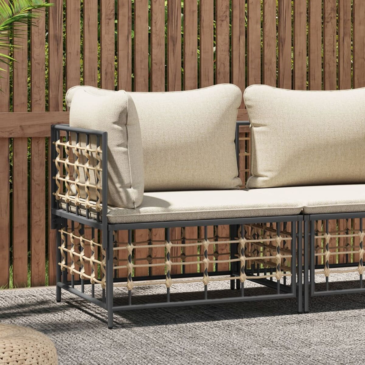 Gartensofa mit grauem Rahmen und gewebten Seiten. Beige Kissen, auf Terrasse, Holzzaun.