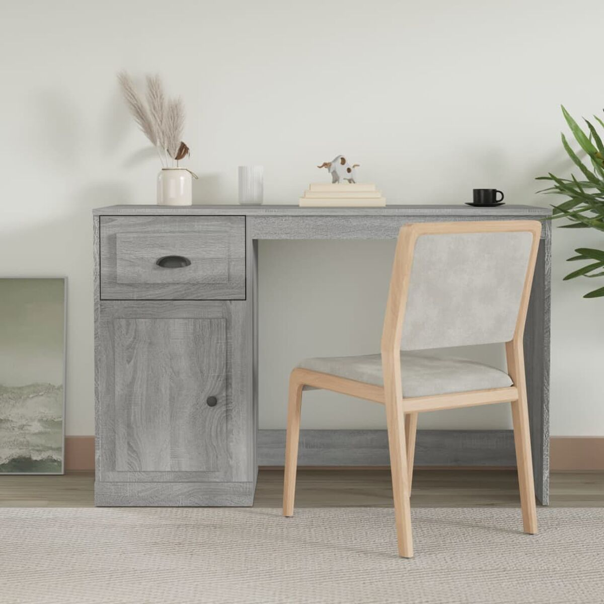 Ein grauer Holzschreibtisch mit Schublade und Tür. Ein Stuhl und einige Gegenstände stehen davor.