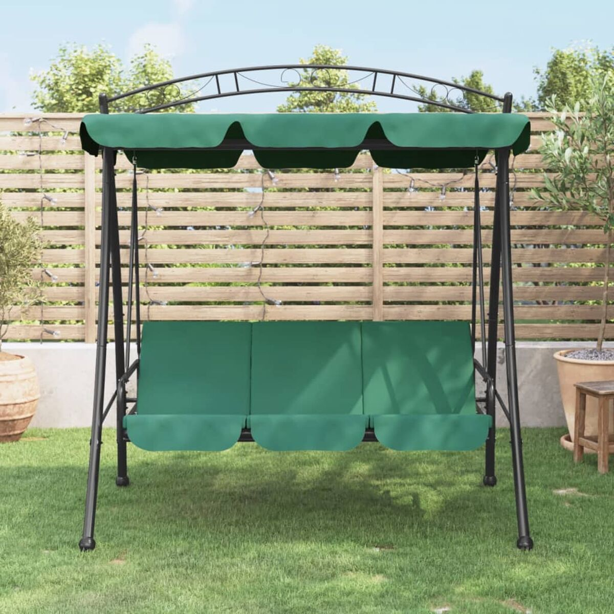 Grünes Schaukelset mit Baldachin, drei Sitzen und einem Metallrahmen, in einem Garten aufgestellt.