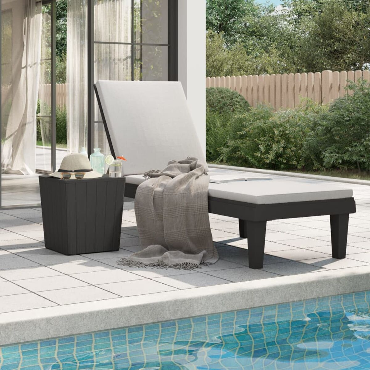 Outdoor-Liegestuhl mit Beistelltisch, Decke und Pool im Hintergrund.