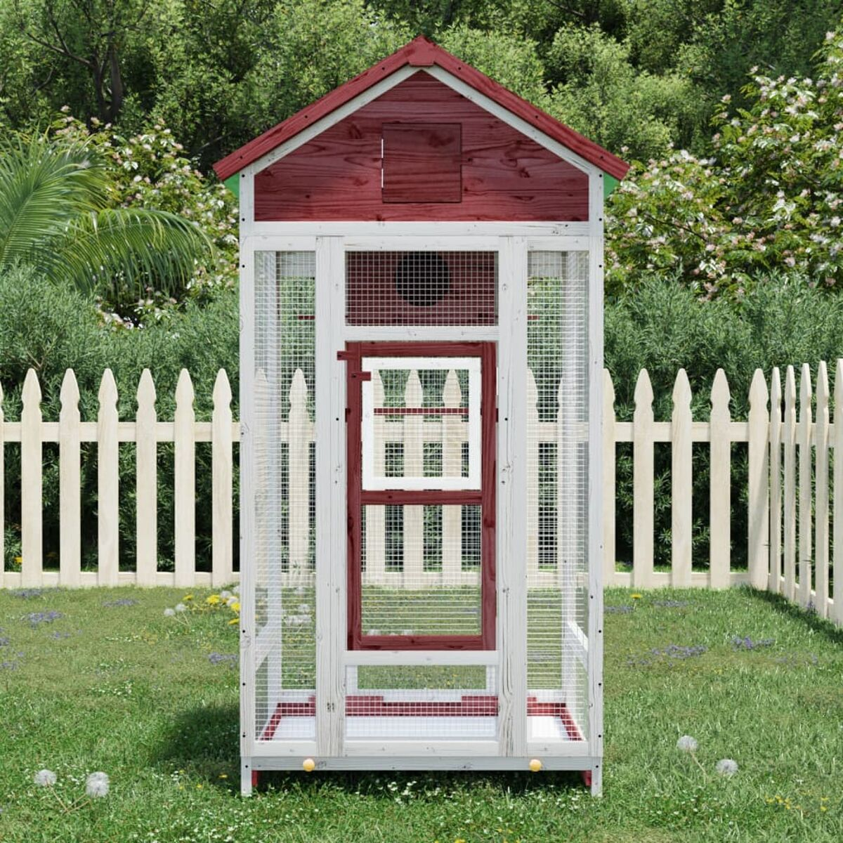 Rot bedachtes Vogelhaus mit weißem Rahmen und Drahtgeflecht. Es steht auf Gras mit einem Zaun dahinter.