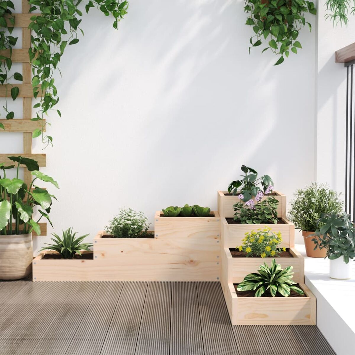 Gestufte Pflanzkästen aus Holz mit Pflanzen vor weißer Wand und Holzterrasse. Hängepflanzen oben.