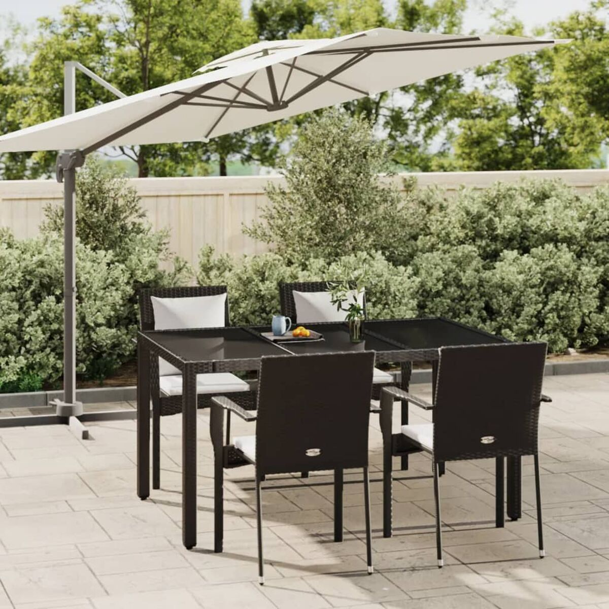 Eine Terrassenszene mit Tisch, Stühlen und einem großen Sonnenschirm. Die Umgebung umfasst Grün und Pflastersteine.