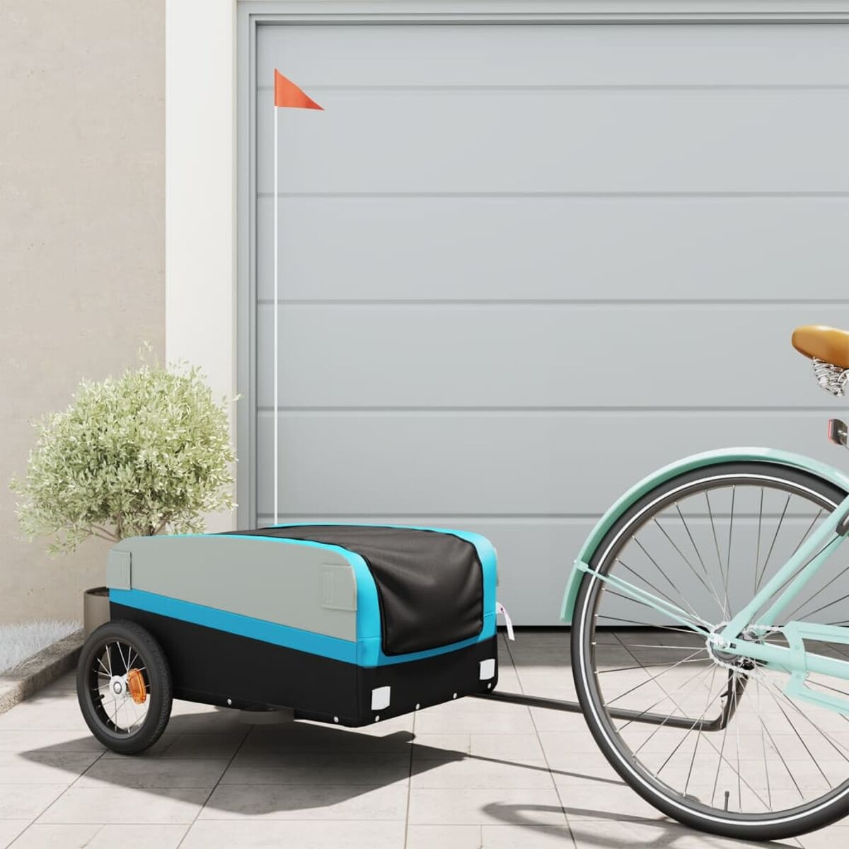Ein Fahrrad mit Anhänger. Der Anhänger ist schwarz und blau und am Fahrrad befestigt. Eine rote Fahne ist am Anhänger befestigt.