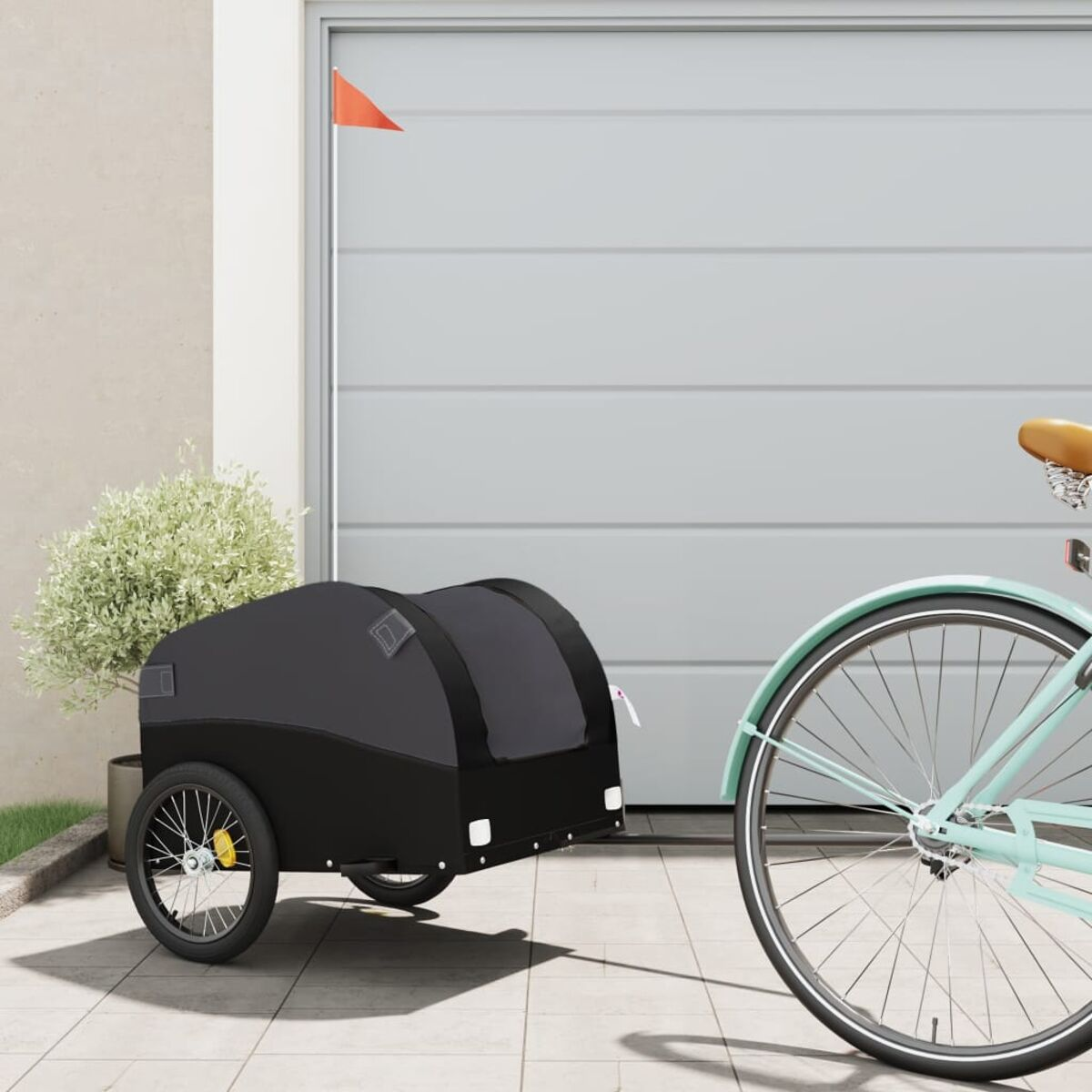 Fahrradanhänger an einem Fahrrad, geparkt in der Nähe einer Garage und einer kleinen Pflanze.