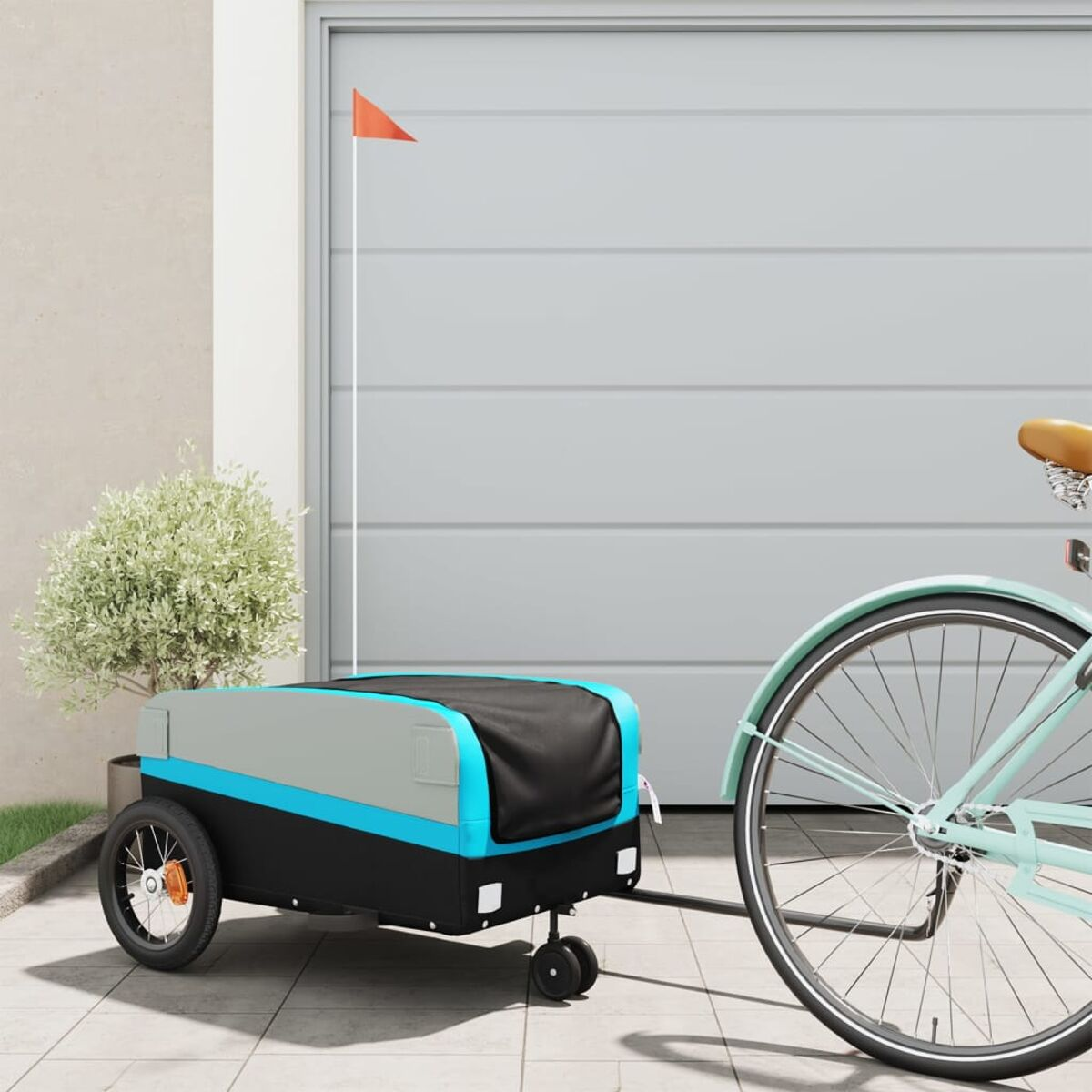 Ein Fahrrad zieht einen Anhänger. Der Anhänger ist schwarz, grau und blau mit einer orangefarbenen Flagge.