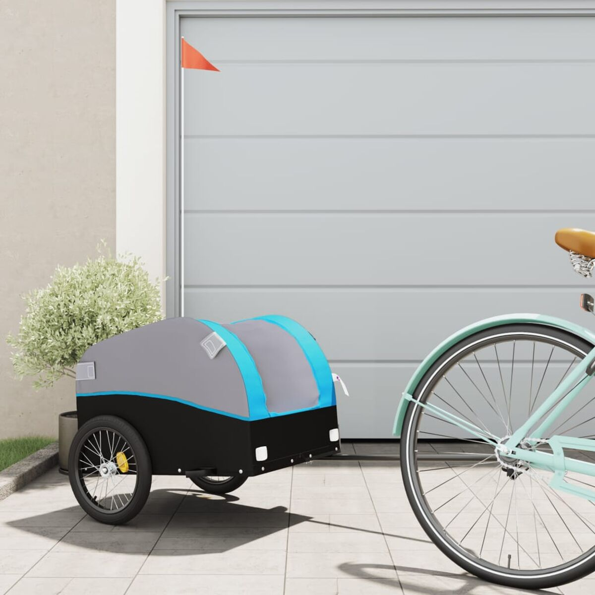 Fahrradanhänger an einem Fahrrad befestigt. Garage im Hintergrund. Blauer und grauer Anhänger.