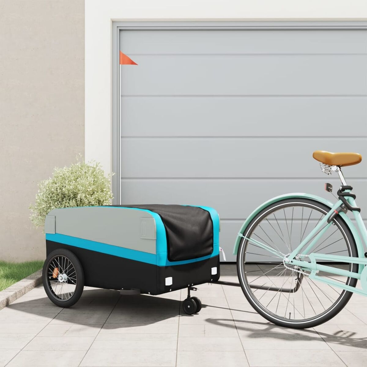 Ein hellblaues Fahrrad mit Anhänger, geparkt vor einem grauen Garagentor mit roter Flagge.