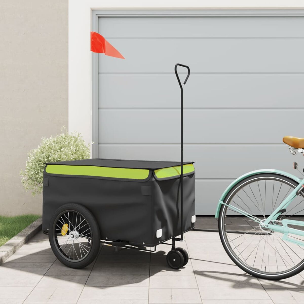 Fahrradanhänger mit Flagge. Schwarzer Anhänger mit grünem Dach. Neben Garage.
