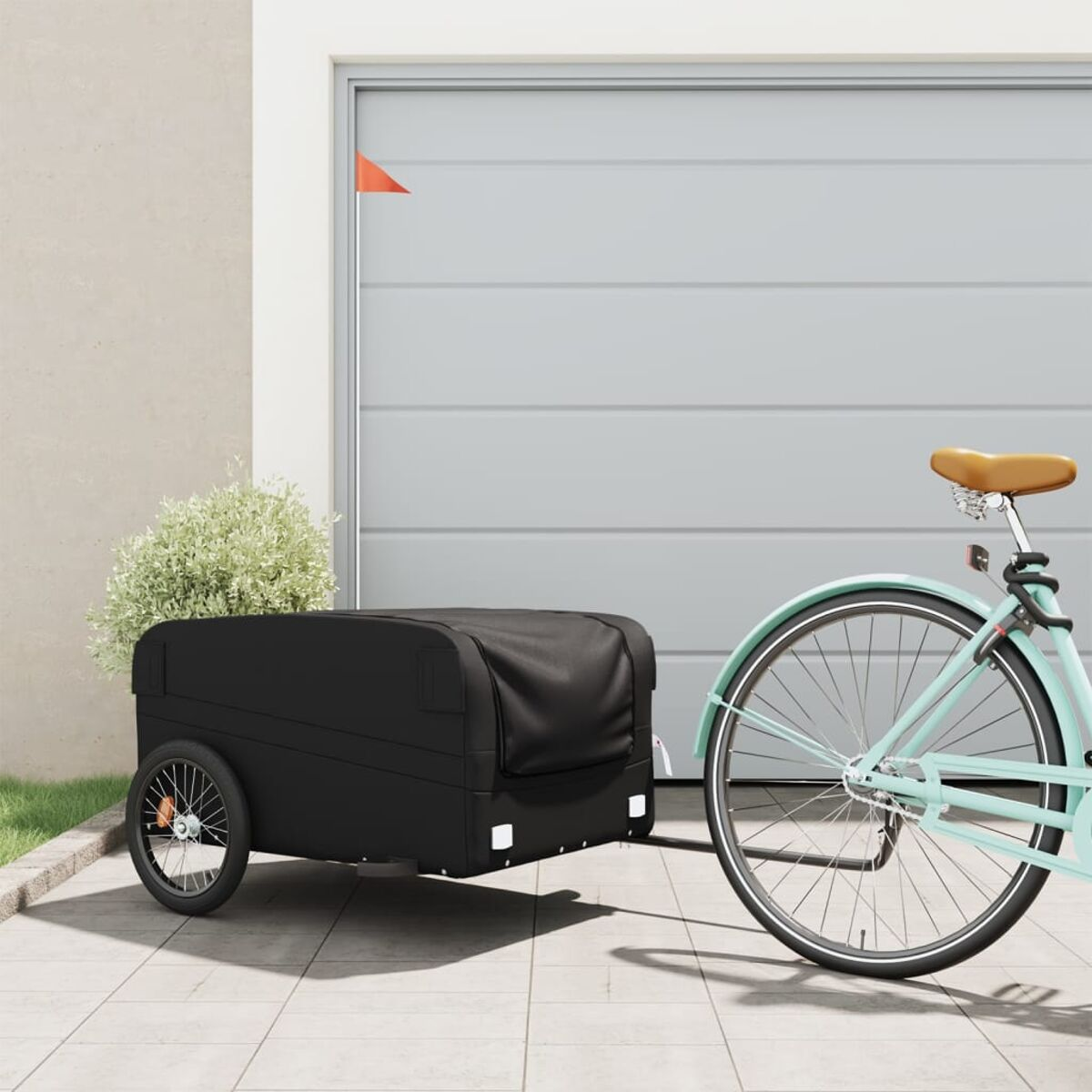 Schwarzer Anhänger an einem blauen Fahrrad. Schwarze Abdeckung auf dem Anhänger. Garagentor im Hintergrund.