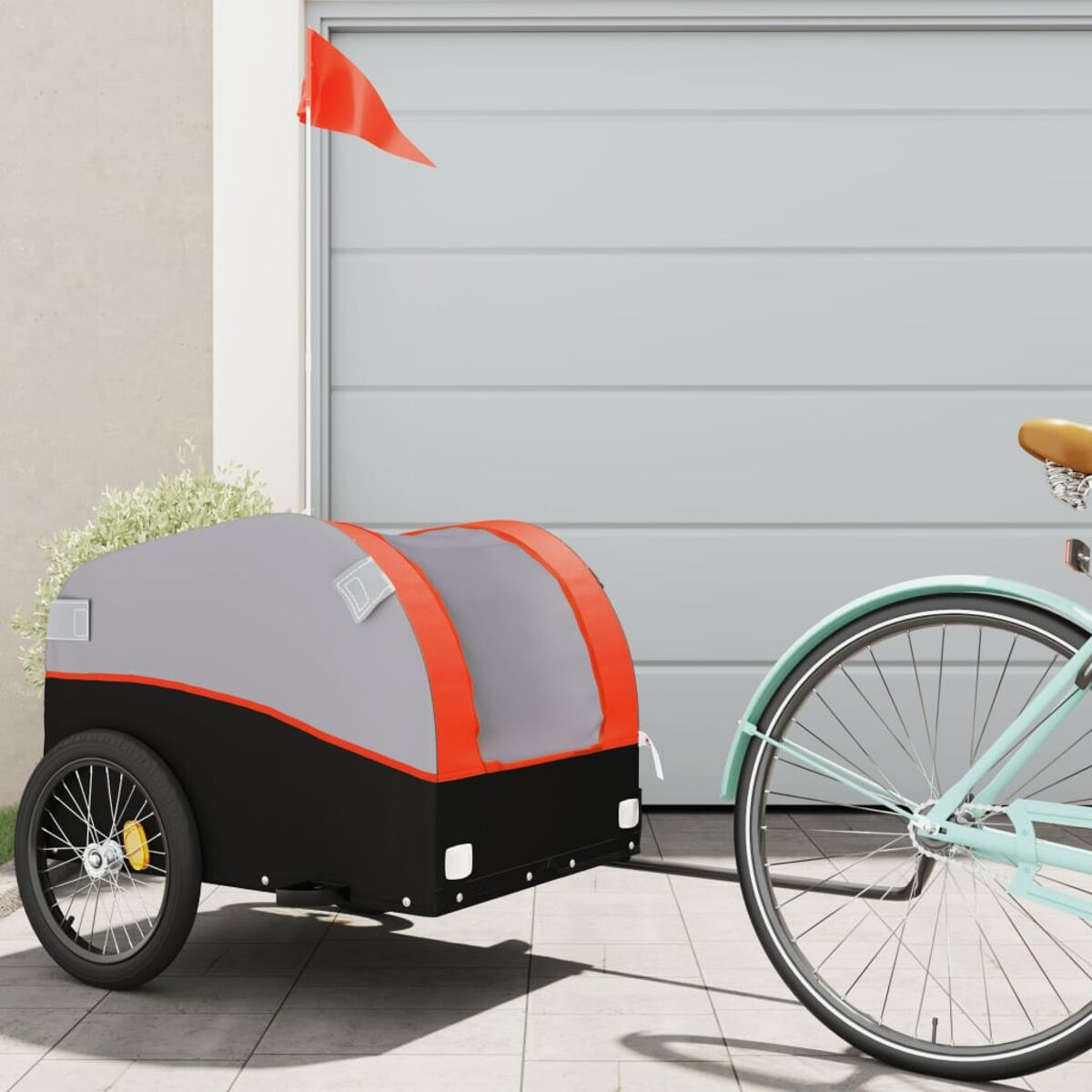 Ein Fahrradanhänger, grau und schwarz, an einem Fahrrad befestigt. Hat eine rote Flagge.