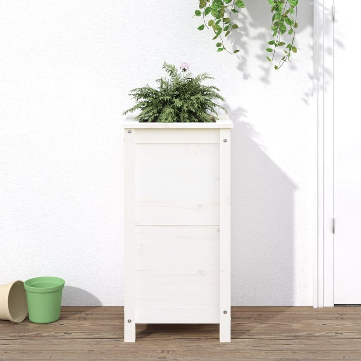 Hoher weißer Holzpflanzer mit Pflanze, vor weißer Wand.