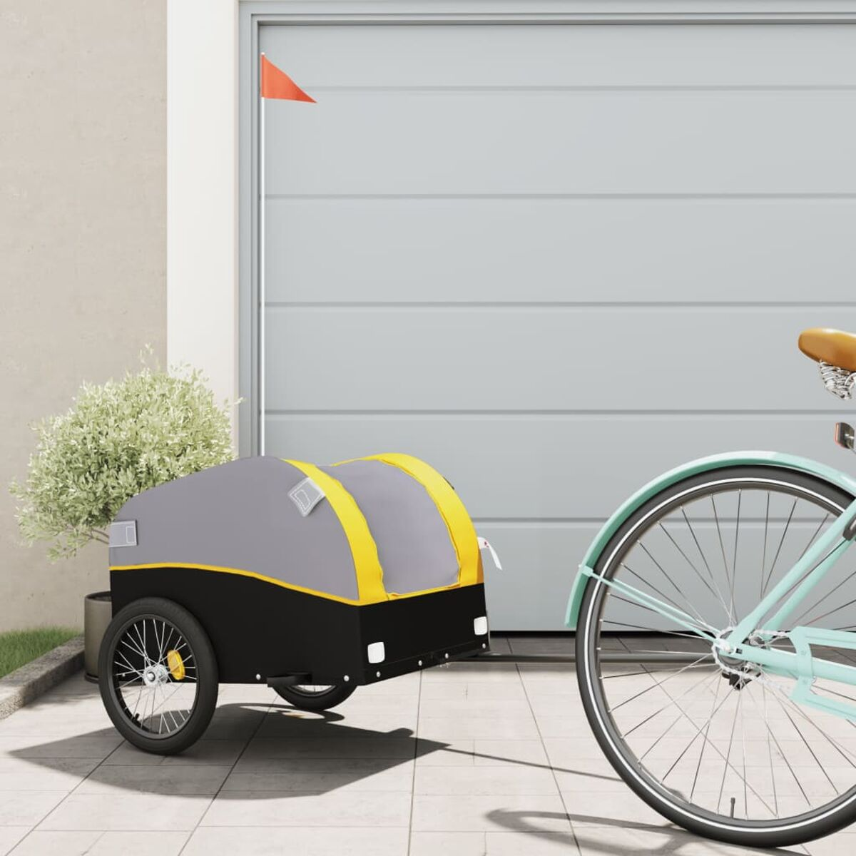 Fahrrad mit Anhänger. Der Anhänger ist grau, gelb und schwarz. Das Fahrrad ist hellblau. Im Hintergrund ist eine Garage.