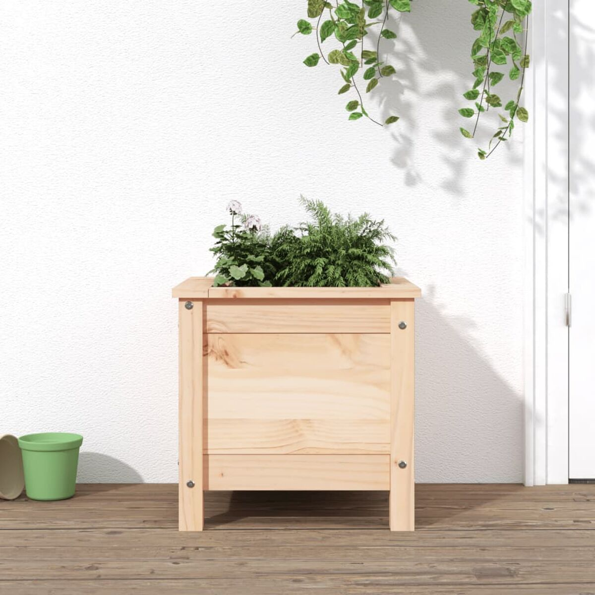 Eine hölzerne Pflanzkasten mit Pflanzen steht auf einer Holzterrasse. Ein grüner Topf steht daneben.