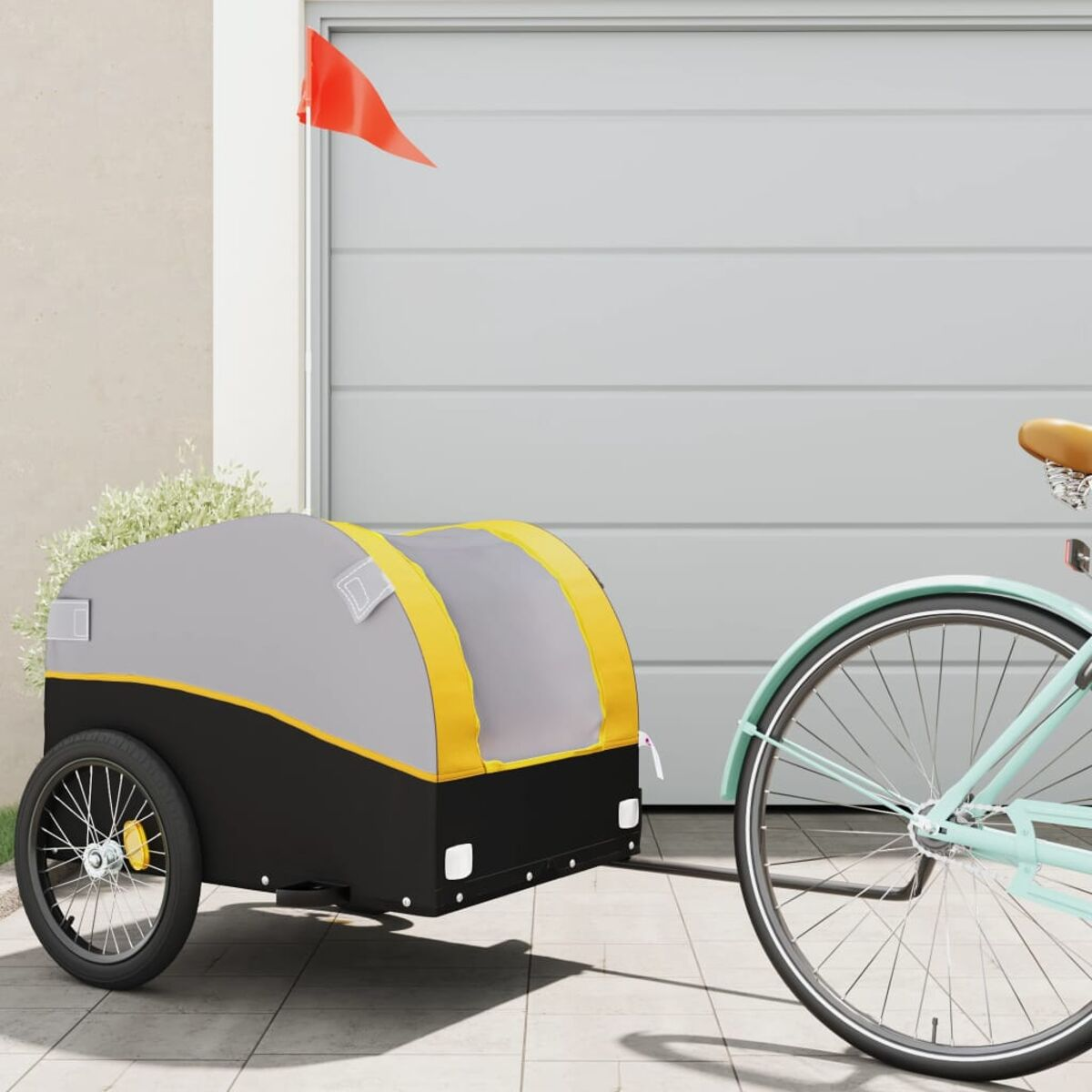 Fahrradanhänger vor einer Garage. Es ist ein mintfarbenes Fahrrad, das einen schwarzen, grauen und gelben Anhänger zieht.