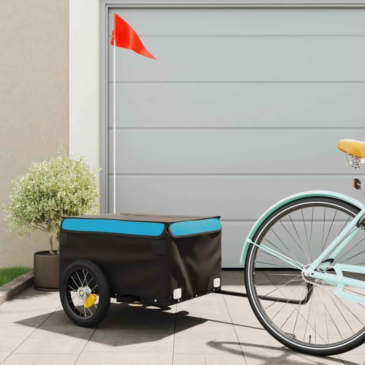 Fahrradanhänger an einem Fahrrad befestigt. Rote Fahne am Anhänger. Garage im Hintergrund.