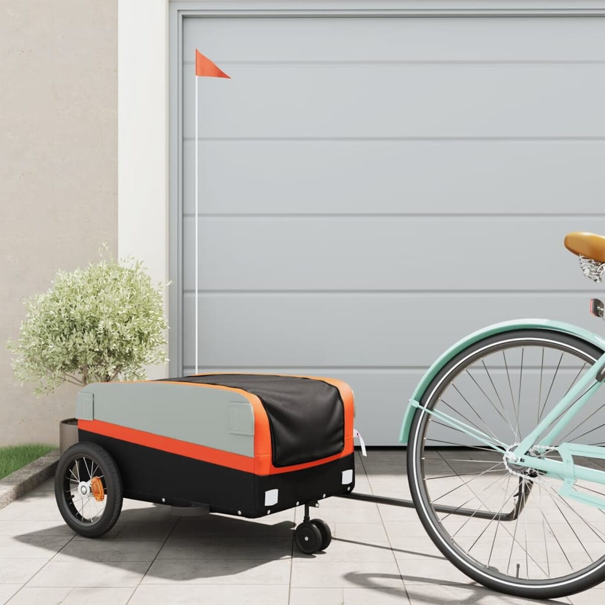 Ein Fahrrad mit Anhänger. Der Anhänger ist grau, schwarz und orange, mit einer kleinen orangefarbenen Flagge.