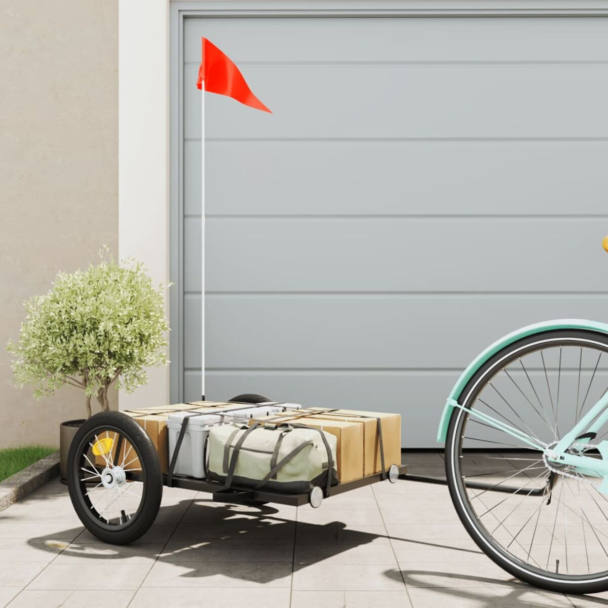 Ein Fahrrad mit einem Anhänger. Eine rote Flagge ist am Anhänger. Garagentor im Hintergrund.