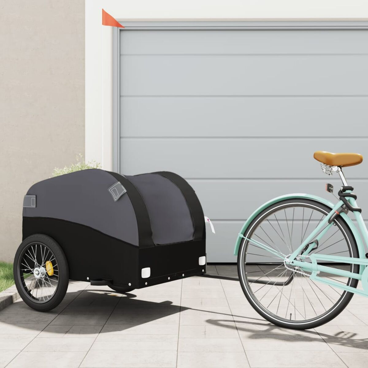 Fahrradanhänger an einem Fahrrad befestigt. Grau-schwarzer Anhänger, mintgrünes Fahrrad. Garagentor im Hintergrund.