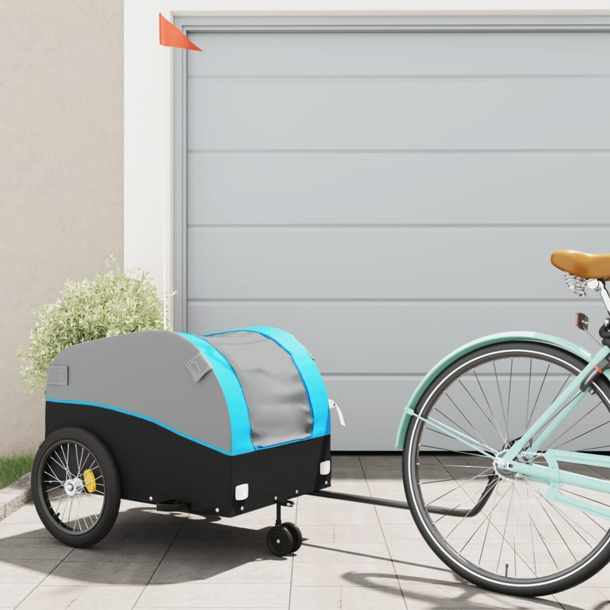 Ein blauer und grauer Anhänger, der an einem mintgrünen Fahrrad befestigt ist. Die Szene ist vor einer Garage.