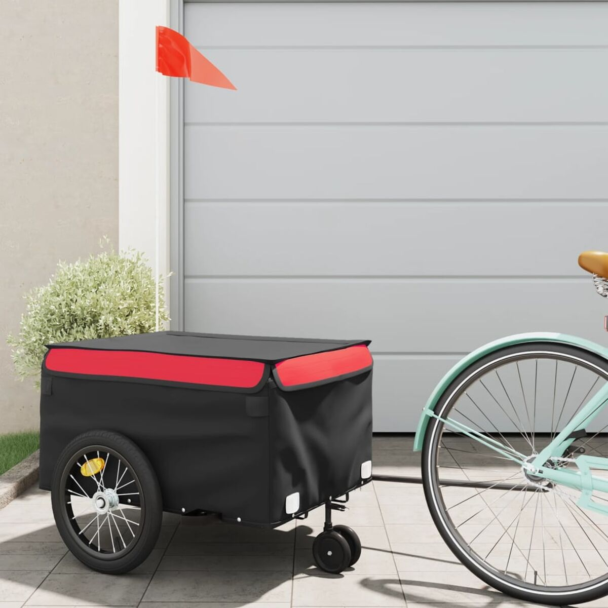 Schwarzer Fahrradanhänger mit roten Akzenten, an einem Fahrrad befestigt. Eine rote Fahne ist befestigt.