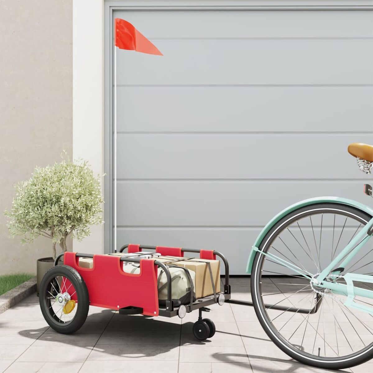 Ein roter Anhänger an einem blauen Fahrrad, mit einer Garage im Hintergrund.