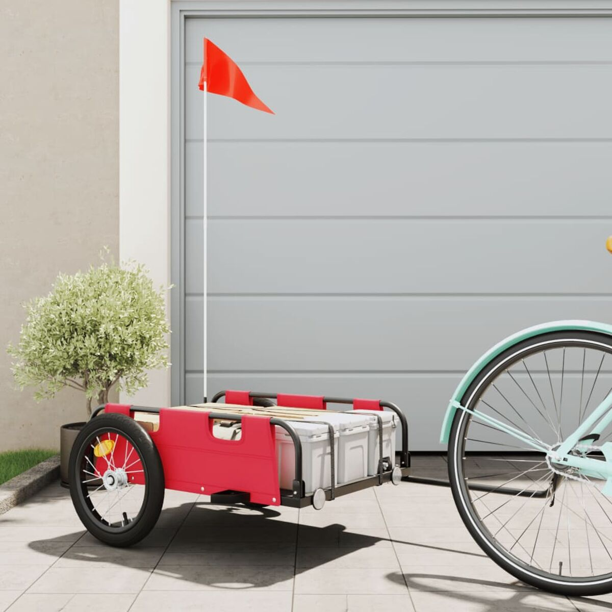 Ein roter Fahrradanhänger mit roter Fahne an einem Fahrrad. Im Hintergrund ist ein Garagentor.