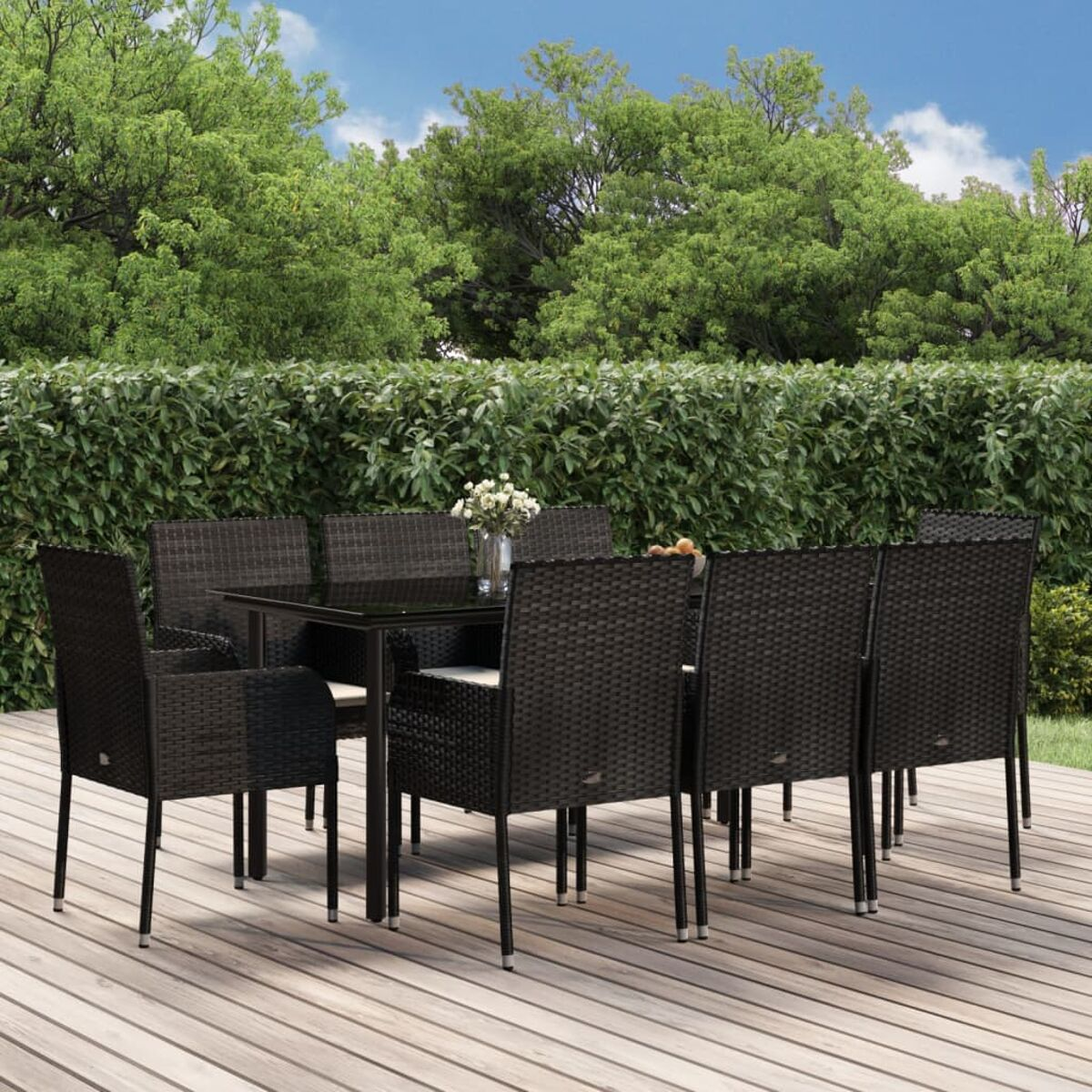Essgruppe im Freien mit schwarzem Tisch und Stühlen auf Holzterrasse, mit grünem Hintergrund.