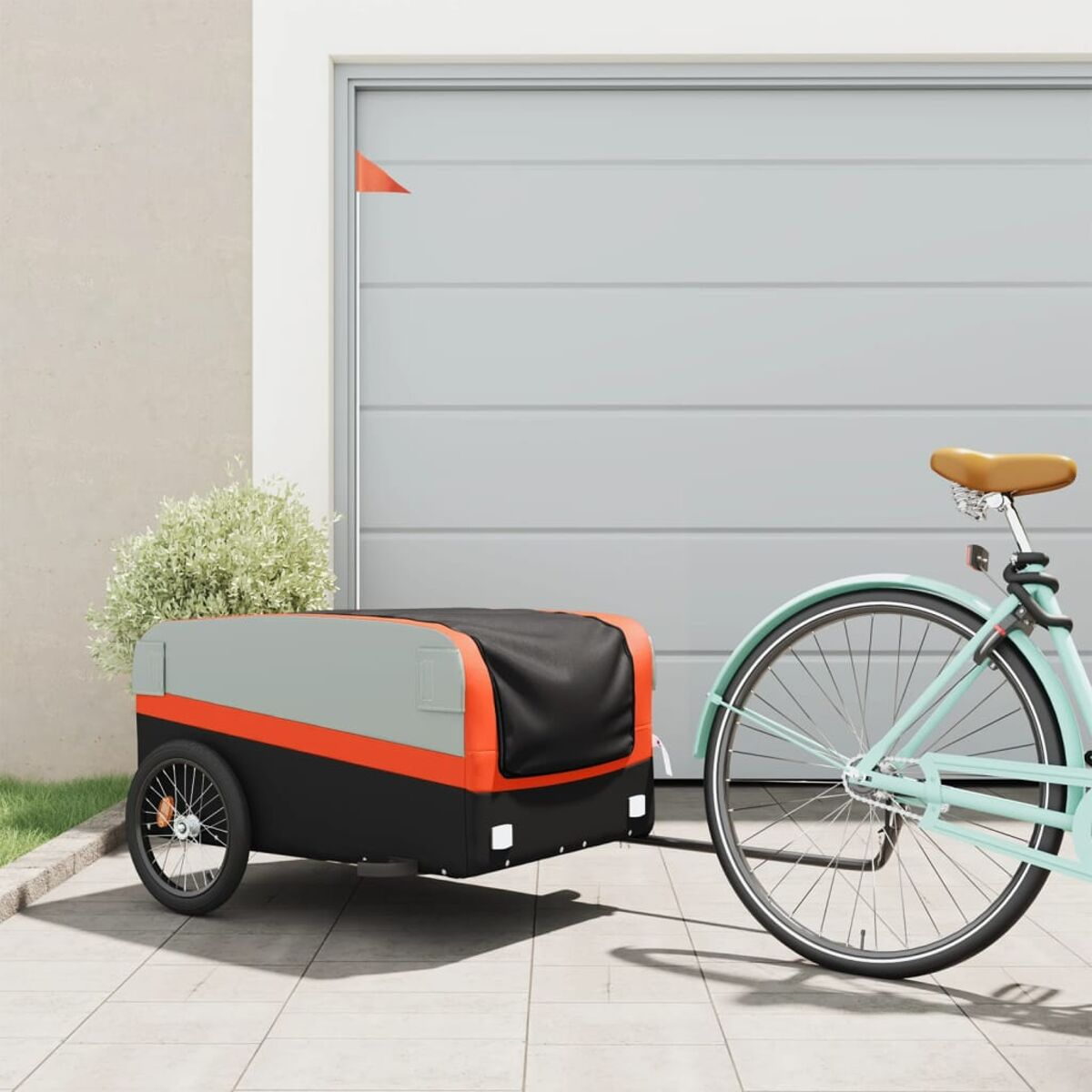 Fahrradanhänger an einem hellblauen Fahrrad, geparkt vor einer Garage. Sonniger Tag.