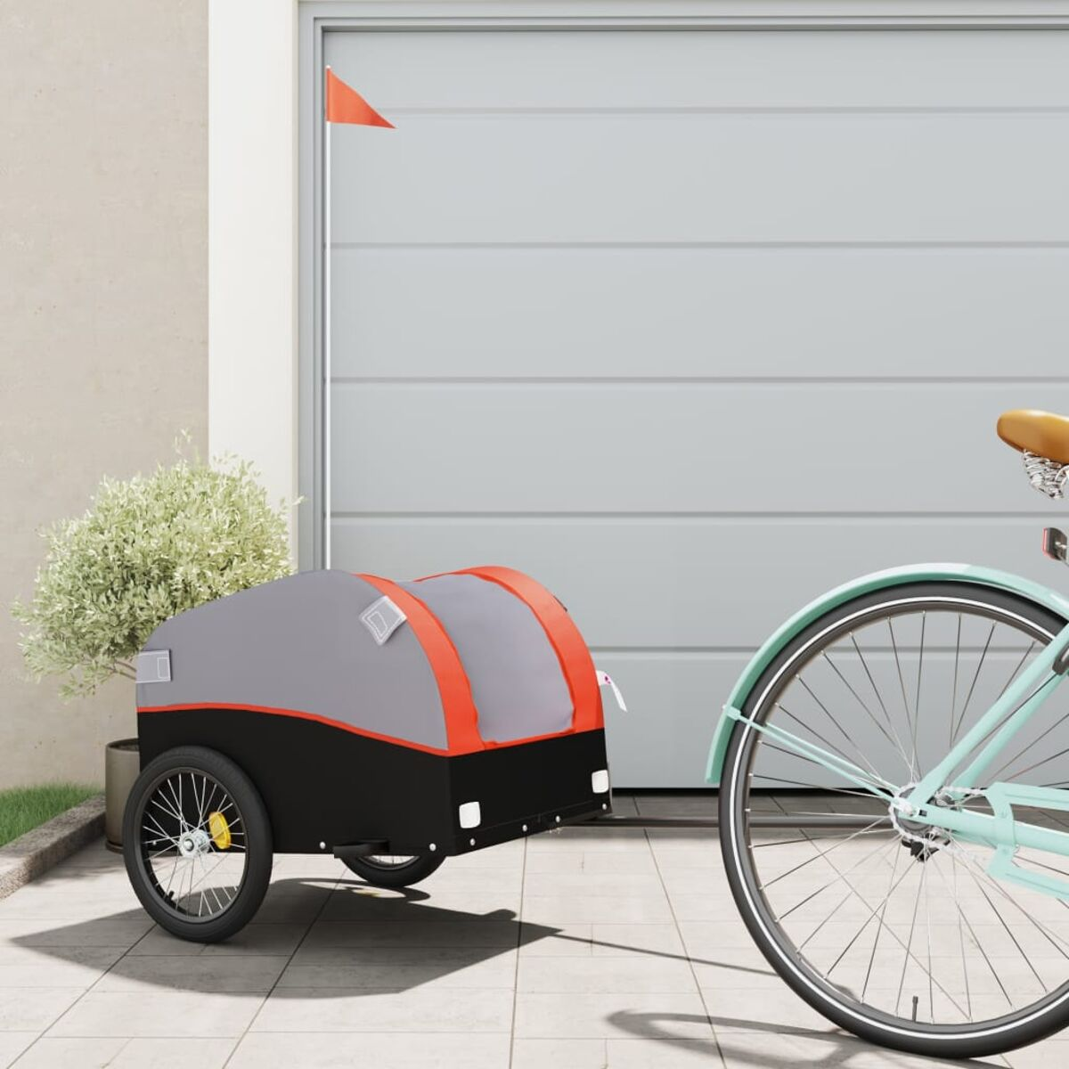 Ein Fahrrad zieht einen grau-schwarzen Anhänger mit einer orangefarbenen Flagge.
